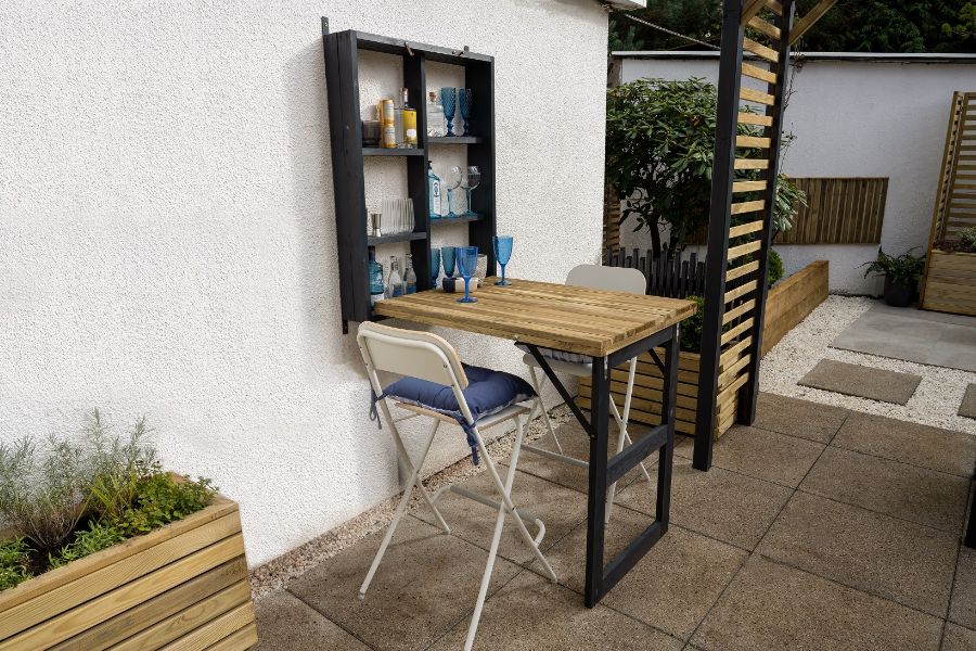 A table and chair outside a house Description automatically generated