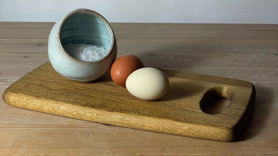 Eggs and a bowl of salt on a cutting board 