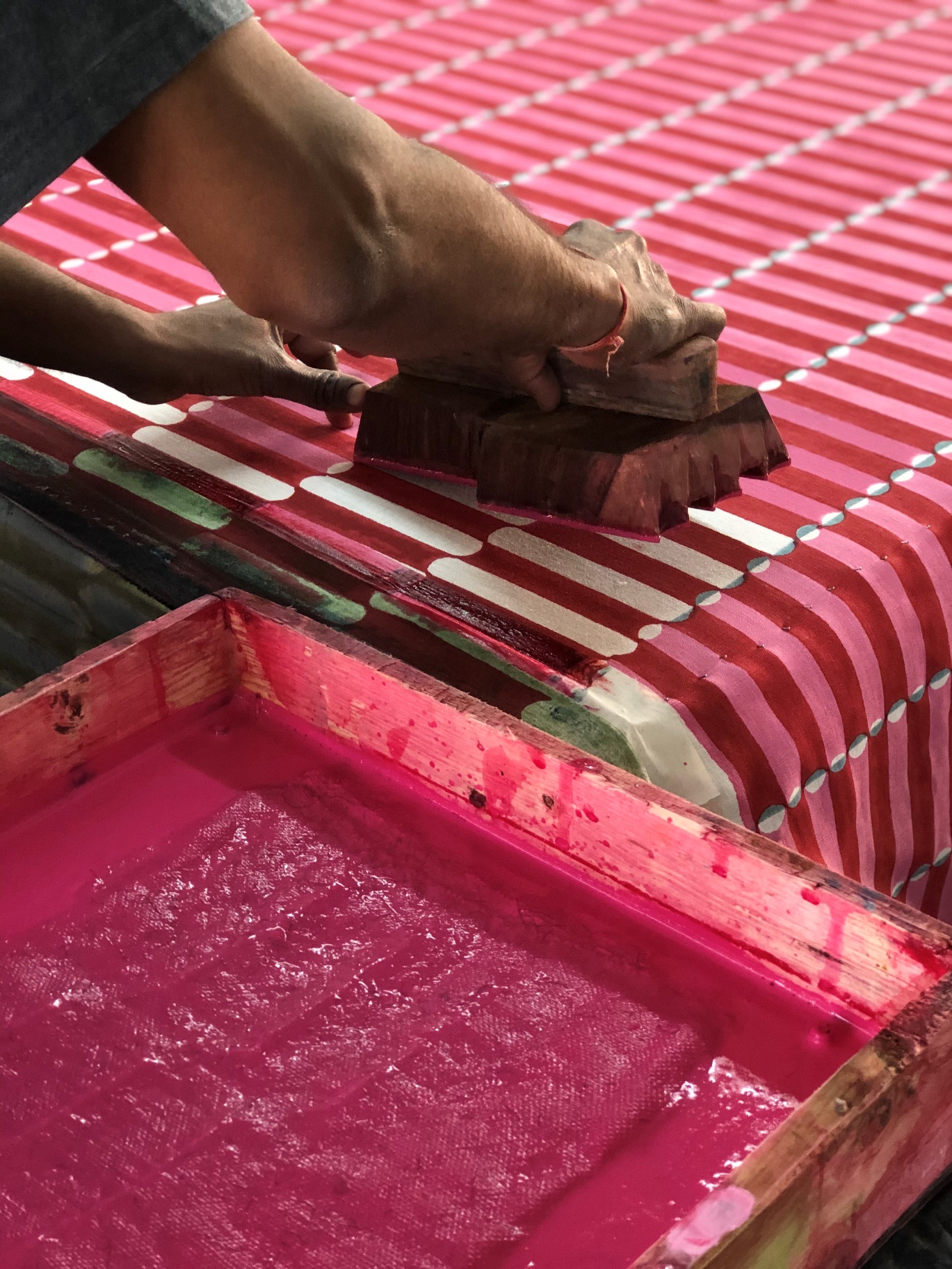 A person using a block to paint a fabric Description automatically generated