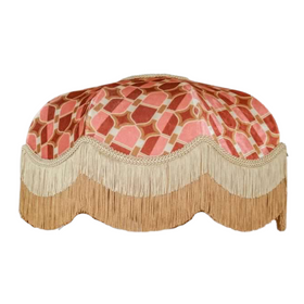A pink and tan fringed bed cover Description automatically generated