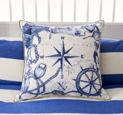 a coastal inspired cushion showing various marine symbols including a compass and a ship's wheel hand drawn in blue and white