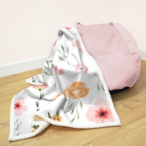 a comfy lookig blanket with a floral design next to a pink beanbag seat