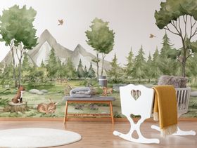 A baby's room with a cute forest-themed wall mural, featuring a mountain in the background