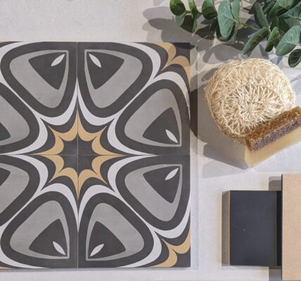 A selection of bathroom tiles in different colours and patterns, with a soap dish and sponge placed on top. The Baked Tile Company logo is visible in the background.