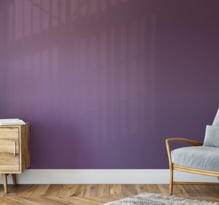 A living room with a bold purple accent wall and a comfy armchair with a lamp next to it.