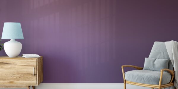 A living room with a bold purple accent wall and a comfy armchair with a lamp next to it.