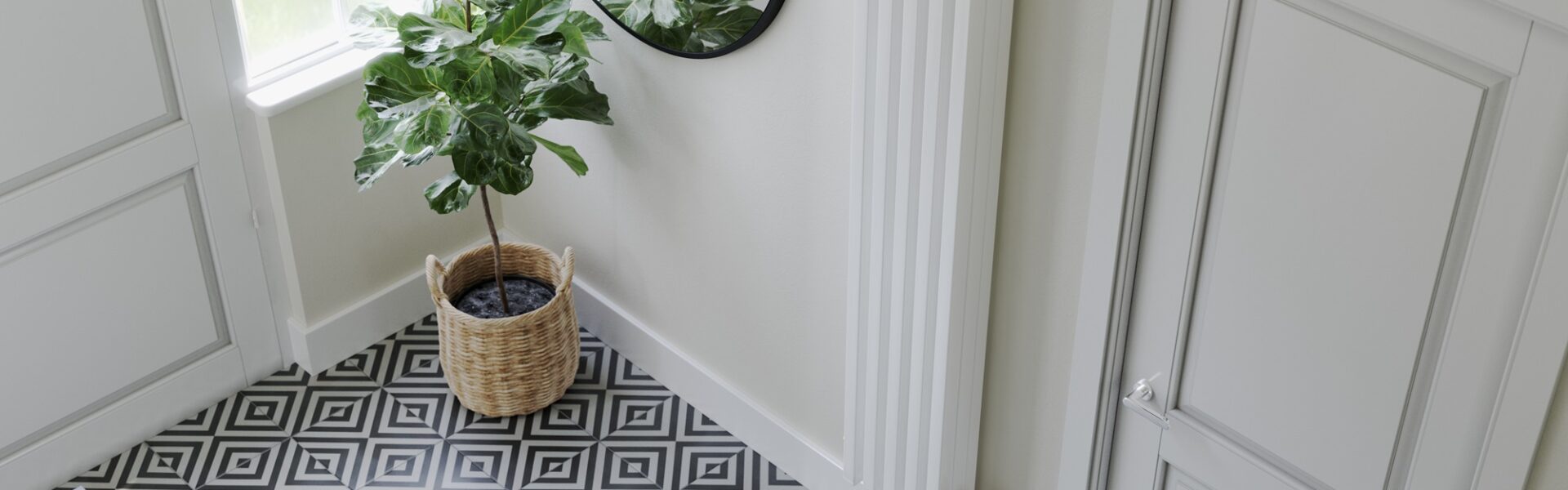 A stylish, narrow, modern radiator on the wall. A potted fiddle-leaf fig plant sitting on a console table beneath a rectangular mirror in a brightly lit hallway.