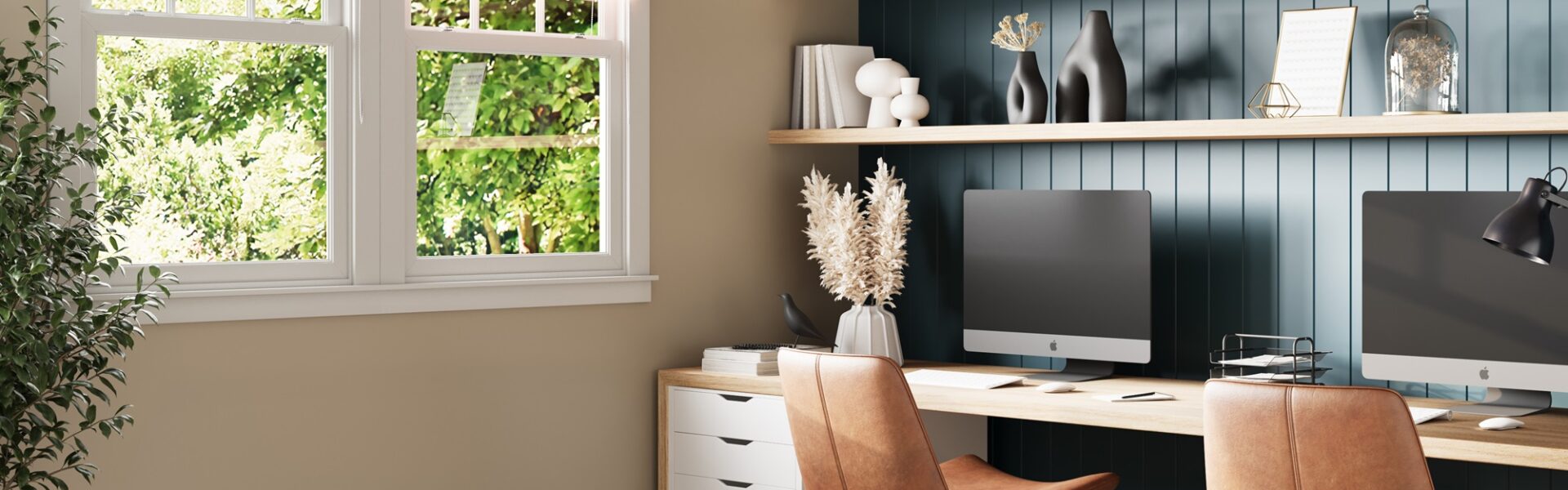 A home office with two desktop computers and two ergonomic chairs facing a window.