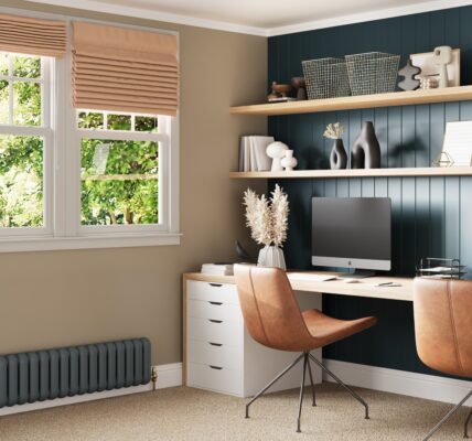 A home office with two desktop computers and two ergonomic chairs facing a window.