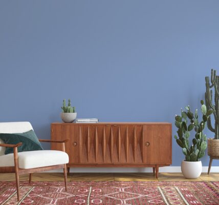 A living room interior with a mid-century modern credenza, a cactus plant and a white armchair