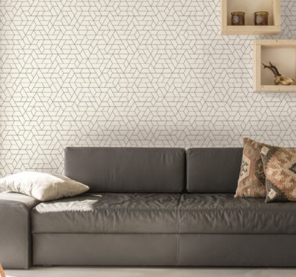 A cosy living room with a brown leather couch and a tall lamp with a white shade in front of a window.