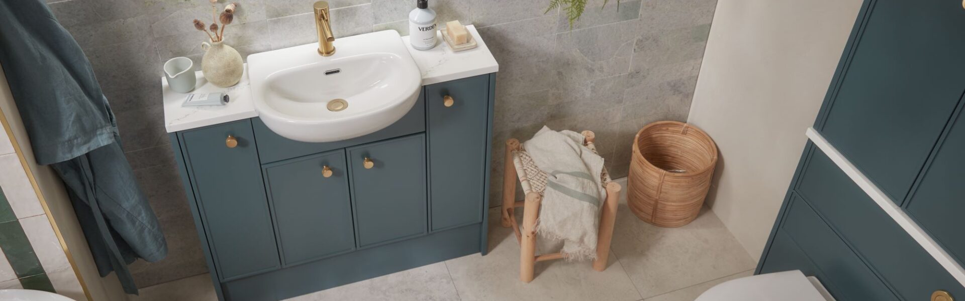 A white bathroom with a sink and toilet. The storage cupboards are a shade of forest green.
