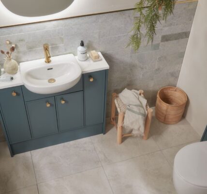 A white bathroom with a sink and toilet. The storage cupboards are a shade of forest green.