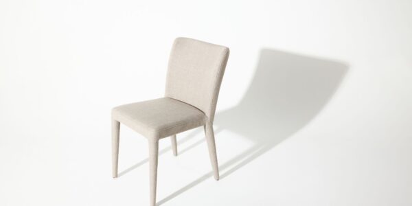 A modern white chair with a simple design casts a shadow on a white background