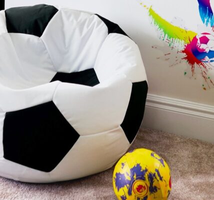 White soccer ball bean bag chair on floor next to soccer ball