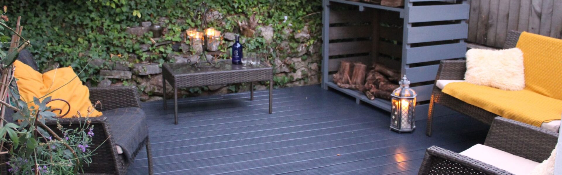 A relaxing outdoor space featuring a dark wicker furniture set and a fire pit. The wicker furniture includes two chairs, a loveseat, and a small table. The fire pit is made of black metal.