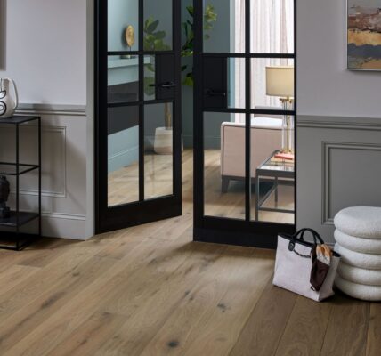 Living space with wooden floor and closed door at the end