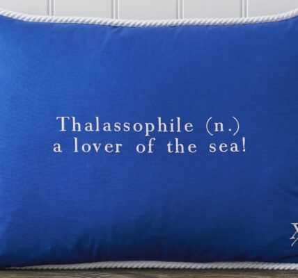 Cushion featuring the word "Thalassophile" embroidered on it in white. The word "Thalassophile" means "a lover of the sea". The cushion also has a white rope trim around the edges.