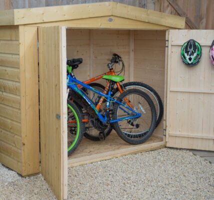 Wooden bike shed with double doors open, revealing two bicycles inside.