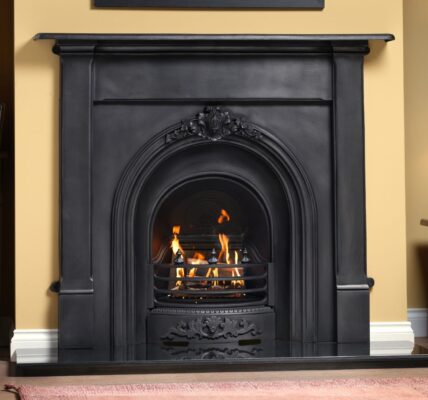 Black cast iron fireplace with a glowing gas fire, set in a traditional living room with a cream wall.