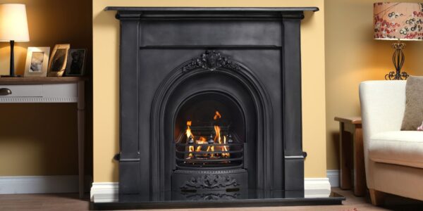 Black cast iron fireplace with a glowing gas fire, set in a traditional living room with a cream wall.