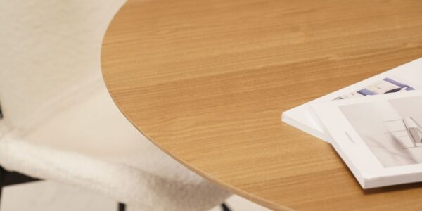 A wooden table with a circular design. This table is finished in a natural colour and is inspired by Scandinavian design