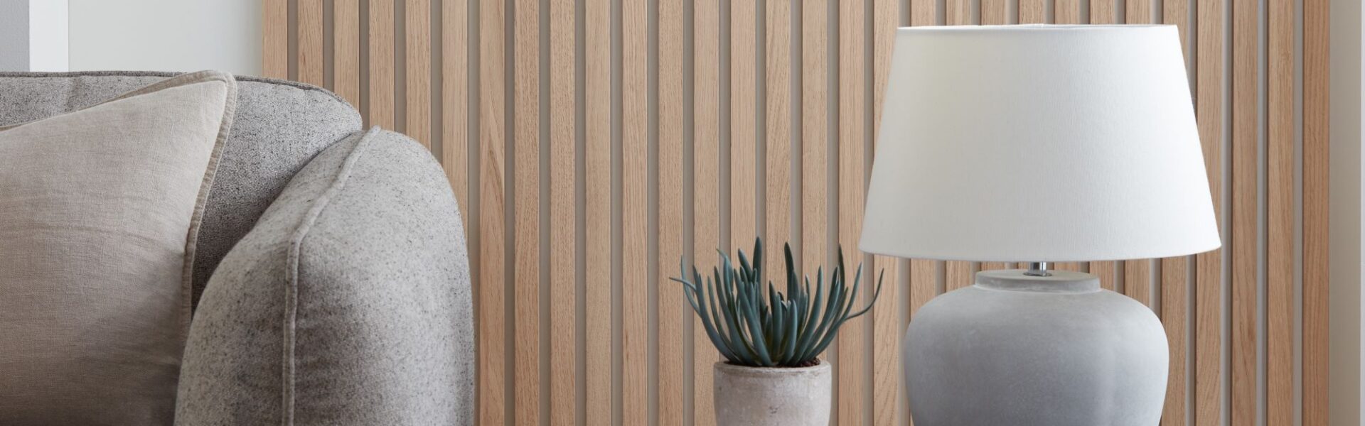 A wood panelled wall with a white lamp and a grey sofa