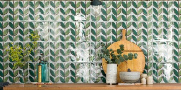 A green and white patterned tile splashback. The tiles feature a leaf-like design and are arranged in a grid pattern. The overall style of the kitchen is vintage and retro, with a focus on natural materials and warm colours.