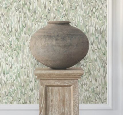A large, earthy-toned clay pot sits on a wooden pedestal against a backdrop of a light green wallpaper with swirling, abstract feather-like patterns.