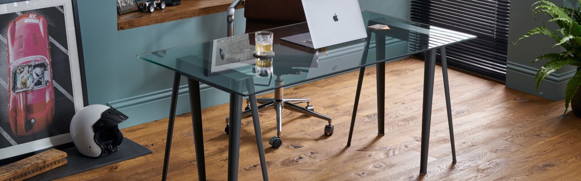 The image shows a modern home office space with dark wood floors and a glass desk.