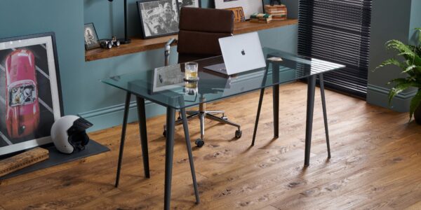 The image shows a modern home office space with dark wood floors and a glass desk.