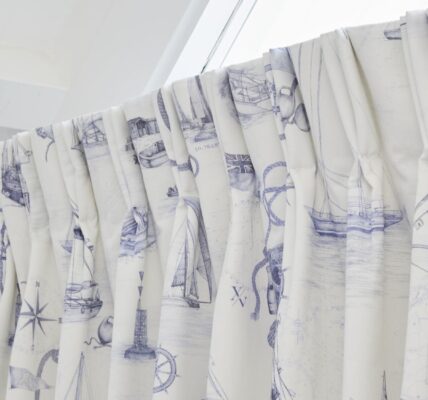 The curtains are white with a blue nautical pattern featuring boats, ships, and anchors. The rod is white and appears to be curved.
