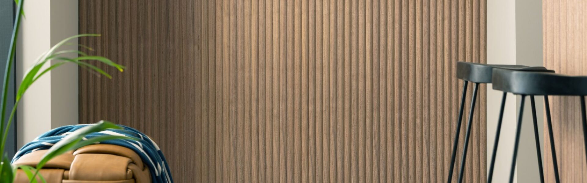 The wall is covered in a vertical wood-panelled design, adding a touch of warmth and texture to the space. The rest of the kitchen seems to be a neutral colour, with light grey countertops and a sleek white backsplash.
