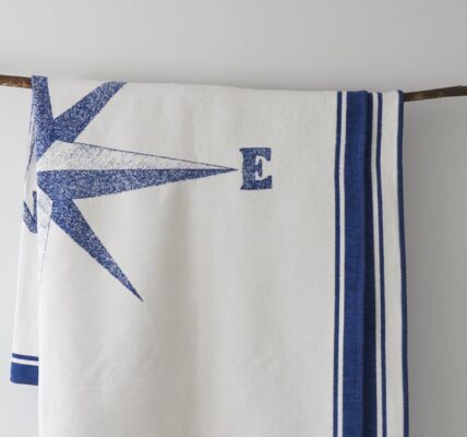 A white blanket with a nautical theme hangs from a branch.