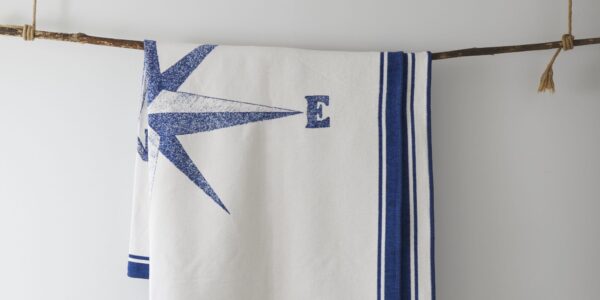 A white blanket with a nautical theme hangs from a branch.