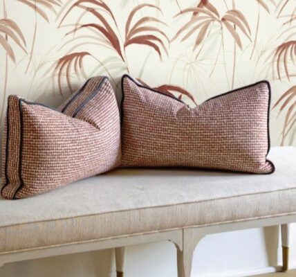 The image creates a serene and inviting atmosphere. The light colours and natural elements of the wallpaper and pillows give a sense of calm and relaxation. The simple design of the bench adds to the overall minimalist aesthetic.