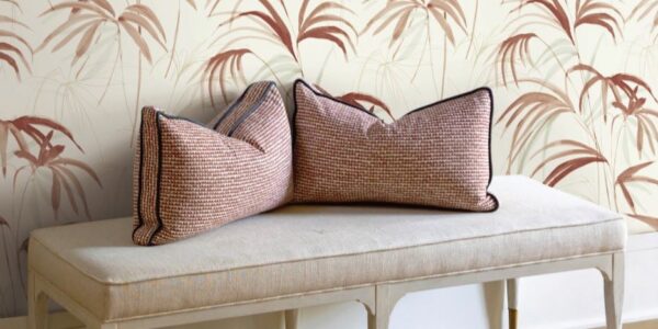 The image creates a serene and inviting atmosphere. The light colours and natural elements of the wallpaper and pillows give a sense of calm and relaxation. The simple design of the bench adds to the overall minimalist aesthetic.