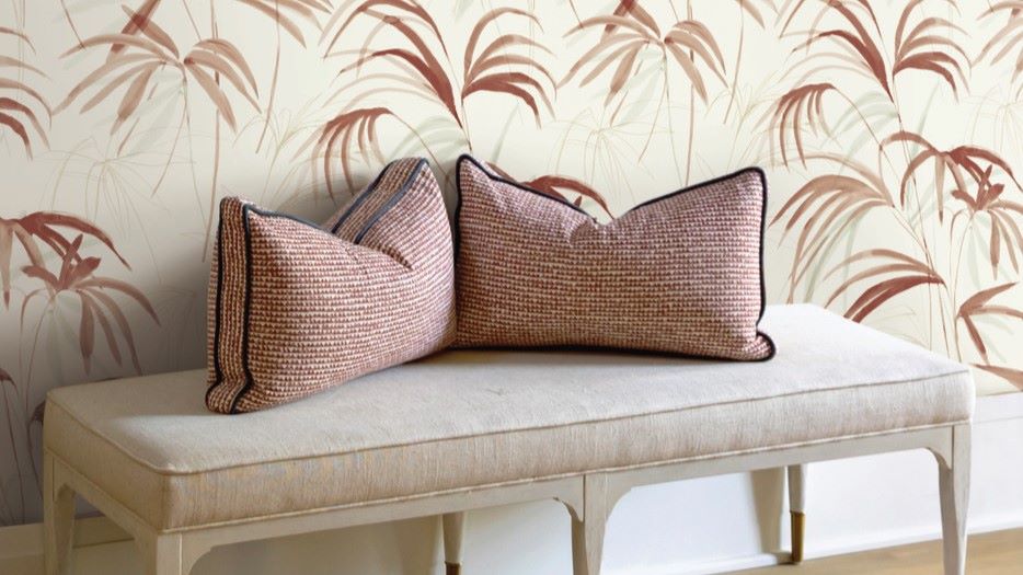 The image creates a serene and inviting atmosphere. The light colours and natural elements of the wallpaper and pillows give a sense of calm and relaxation. The simple design of the bench adds to the overall minimalist aesthetic.