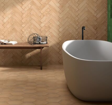 Modern bathroom with a freestanding white tub and a herringbone terracotta tile wall.