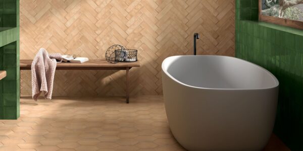 Modern bathroom with a freestanding white tub and a herringbone terracotta tile wall.