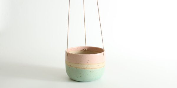 A hanging planter with a pastel pink, cream, and mint green colour block design