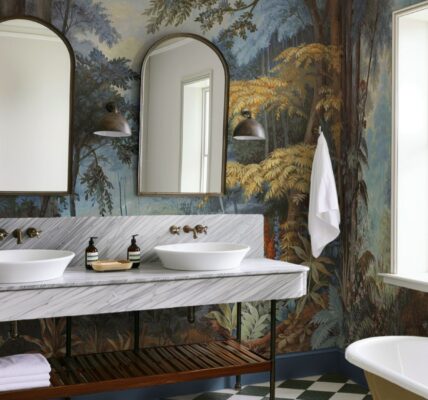 The wallpaper features a nature-inspired mural with trees and foliage in various shades of blue, green, brown, and yellow. This creates a strong visual impact and adds depth to the room.