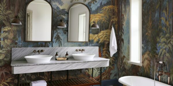 The wallpaper features a nature-inspired mural with trees and foliage in various shades of blue, green, brown, and yellow. This creates a strong visual impact and adds depth to the room.