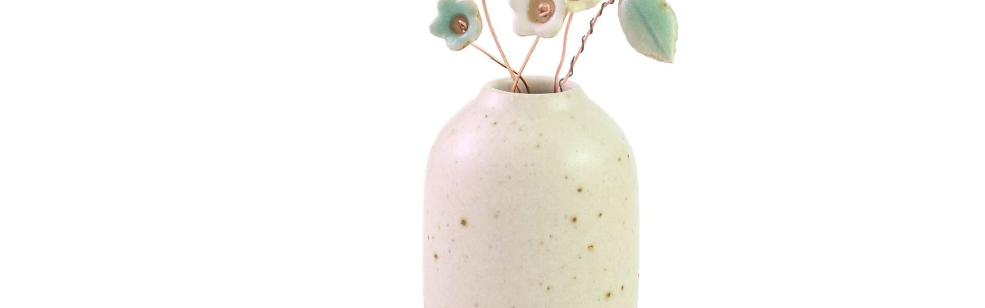 A small, cream-colored ceramic vase with speckled detailing, holding several delicate, pastel-coloured ceramic wildflower stems. The flowers are in shades of blue, pink, and yellow, and are attached to thin, brown wire stems. One stem also features a small, green ceramic leaf.