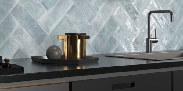 The backsplash features light blue or grey tiles arranged in a herringbone pattern. The tiles have a distinctive textured, almost wavy or rippled surface, giving them a handmade or artisanal appearance.