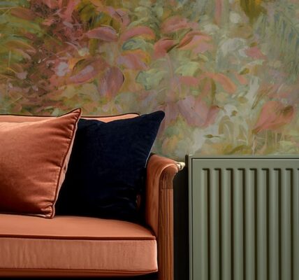 The wallpaper behind the sofa and radiator features a painterly floral design. The colours are soft and muted, with shades of pink, green, and a hint of yellow. The pattern appears abstract, with blurred edges and a watercolour-like quality.