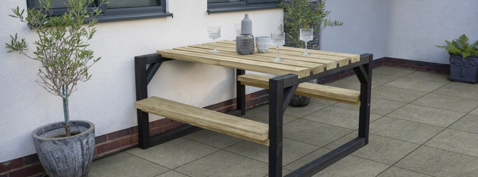A wooden picnic table and attached benches on a patio, perfect for summer dining.
