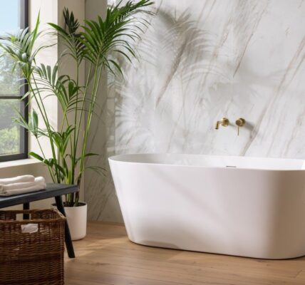 : A bright and airy bathroom featuring a freestanding white oval bathtub positioned in front of a wall with a light marble pattern.