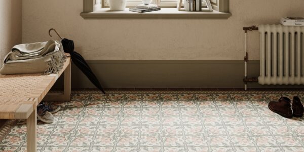 A brightly lit entryway features patterned floor tiles in muted pink, grey, and cream, arranged in repeating floral and geometric designs.