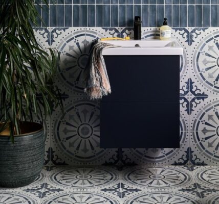 The wall features two types of tiles: a dark blue, possibly subway-style, tile on the upper part, and a patterned tile with a circular, almost mandala-like design in shades of blue and white on the lower half. This same patterned tile extends across the entire floor.